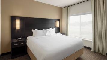 A hotel room with a large bed, a nightstand with a phone, and a window with curtains.