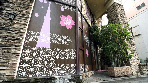 A building facade with decorative patterns, a stone wall, and a potted plant. - Hotel mju - Adults Only (Tokyo)