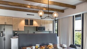 Una cucina moderna con travi in legno, un'area pranzo con tavolo apparecchiato per la colazione e vista sul verde.