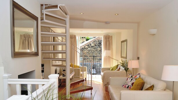 Ein modernes Wohnzimmer mit Treppe, Sofa, Couchtisch und Lampe.
