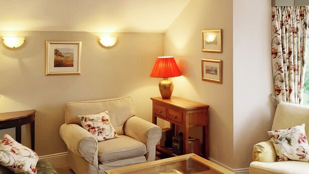 A living room with a sofa, a coffee table, a lamp, and wall-mounted picture frames. - 1 bedroom accommodation in Windermere (Windermere)