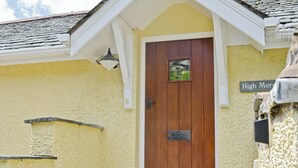 A yellow building with a wooden door, a small window, and a sign reading 'High Mere.' - 1 bedroom accommodation in Windermere (Windermere)