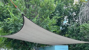 Um deck com mobiliário de exterior, um armário azul e uma grande vela de proteção solar.