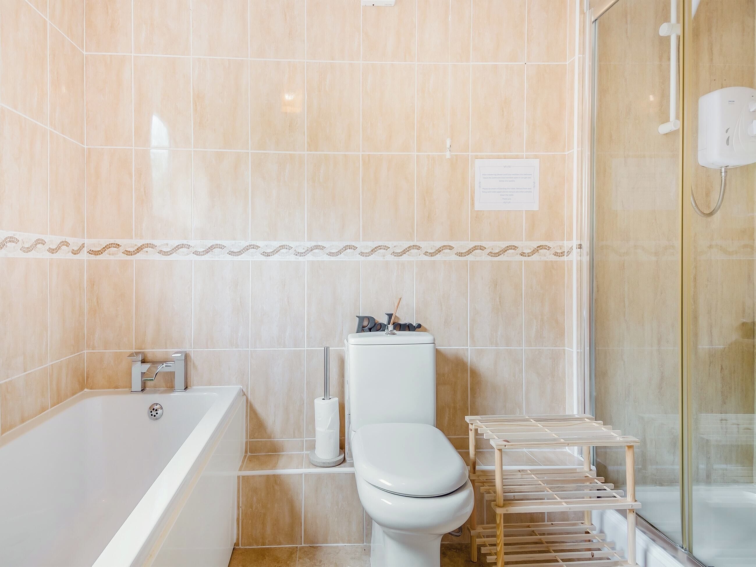 A bathroom with a bathtub, toilet, and a glass shower enclosure.