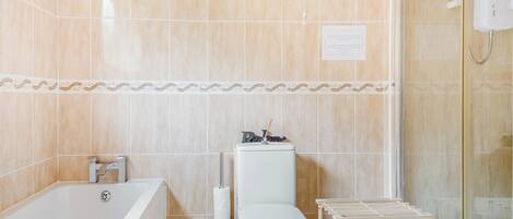 A bathroom with a bathtub, toilet, and a glass shower enclosure.