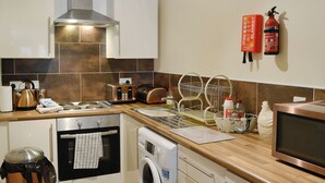 Eine moderne Küche mit Edelstahlgeräten, einem Geschirrspüler und einer Mikrowelle. Zwei Feuerlöscher sind an der Wand angebracht.