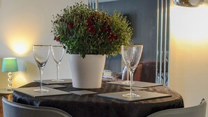 Ein Tisch mit einer weißen Vase voller Blumen, zwei leere Weingläser und einer dunklen Tischdecke.