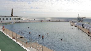 A large public swimming pool with multiple lanes and a surrounding walkway.