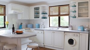 A kitchen with white cabinets, a built-in washing machine, a coffee maker, and a toaster. - Rosecraddoc Manor - Lakeview (Near Liskeard)