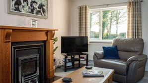 A living room with a fireplace, a television, a leather sofa, and a coffee table. - 3 bedroom accommodation in Pontrug, near Caernarfon (Pontrug, near Caernarfon)