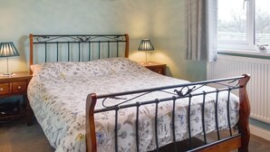 A bedroom with a bed, two bedside tables, a window with curtains, a radiator, and a painting on the wall. - 3 bedroom accommodation in Pontrug, near Caernarfon (Pontrug, near Caernarfon)