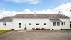 A two-story white house with a gravel driveway and potted plants in front. - 3 bedroom accommodation in Pontrug, near Caernarfon (Pontrug, near Caernarfon)