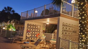 A two-story building with a balcony, outdoor seating area, and decorative lighting.