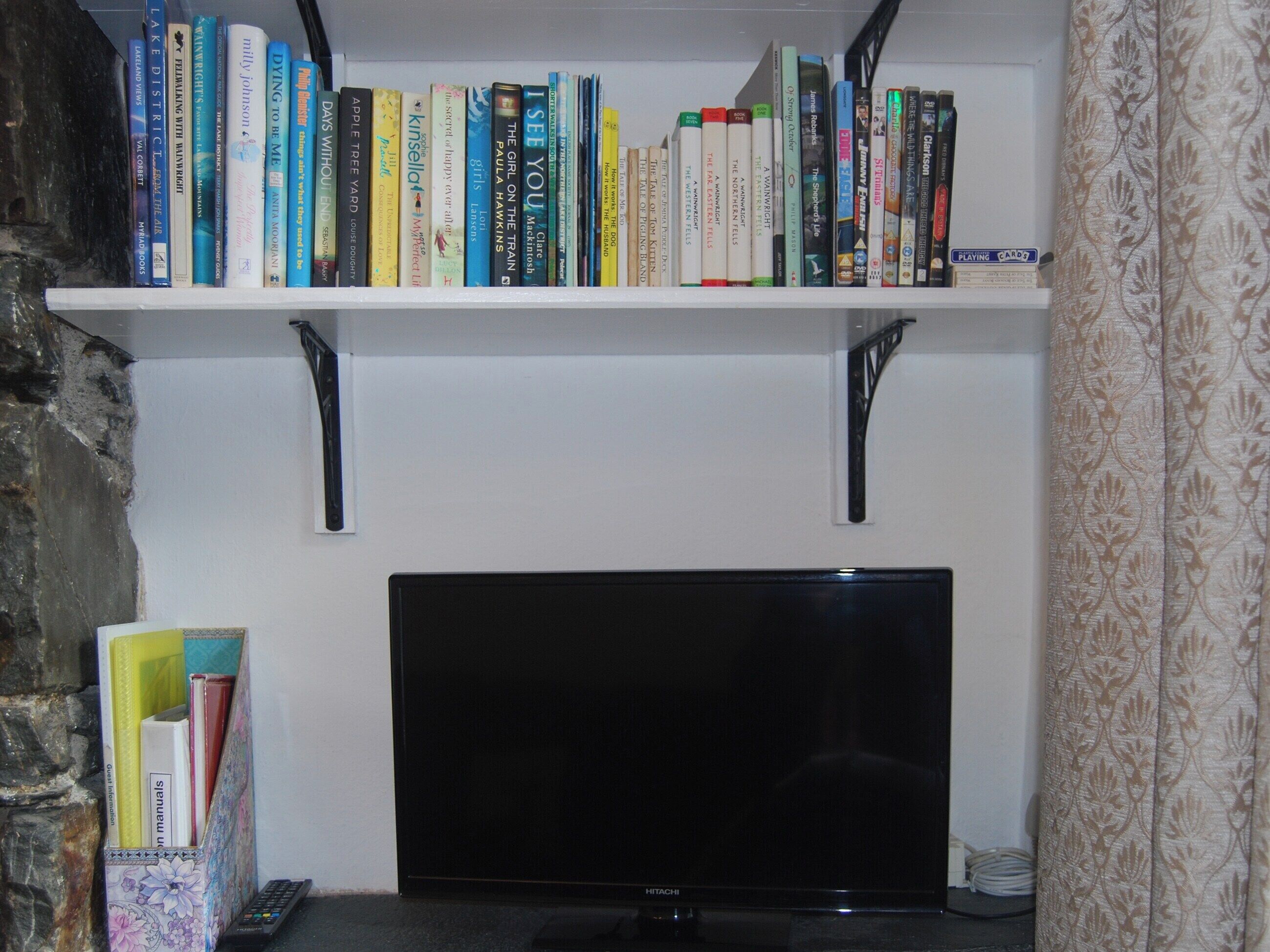 A bookshelf with various books and a television set below it.