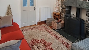 A cozy living room with a red sofa, a patterned rug, a fireplace, and a Christmas tree.