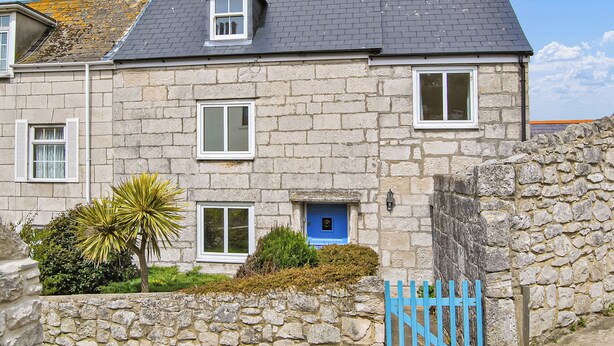 A stone building with a grey tiled roof, a small window, and a blue door. - 3 bedroom accommodation in Portland (Portland)