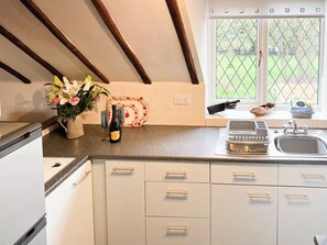 A kitchen with a window, a wine bottle, and a flower vase. - 2 bedroom accommodation in Addlethorpe (Addlethorpe)