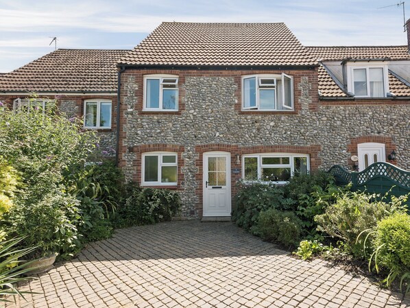 A two-story house with a stone facade, multiple windows, and a paved driveway. - 3 bedroom accommodation in Weybourne, near Holt (Weybourne, near Holt)