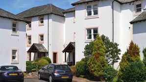 A row of white buildings with multiple windows and a parked car in front. - James' Retreat (was12 Elm Court) (Keswick)