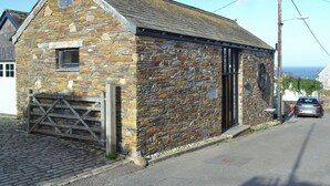 A stone building with a sloped roof, a wooden door, and a small window. - 1 bedroom accommodation in Port Isaac (Port Isaac)