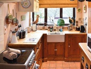 A kitchen with wooden cabinets, a stove, a sink, and various kitchen items.