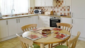 A kitchen with white cabinets, a microwave, a sink, and a dining table with chairs.