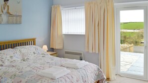 A bedroom with a bed, a nightstand, a radiator, and a window with curtains.