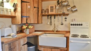 A compact kitchen with wooden cabinets, a white stove, and various kitchen utensils hanging on the wall. - Byre Cottage - 29410 (Stelling Minnis, near Canterbury)