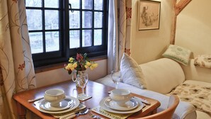 A dining table set with white plates, bowls, and cutlery, a vase with flowers, and a glass of water. - Byre Cottage - 29410 (Stelling Minnis, near Canterbury)