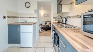 Une cuisine moderne équipée d’une cuisinière intégrée, d’un réfrigérateur et d’un four à micro-ondes. Il y a une horloge au mur et une fenêtre au-dessus de l’évier.