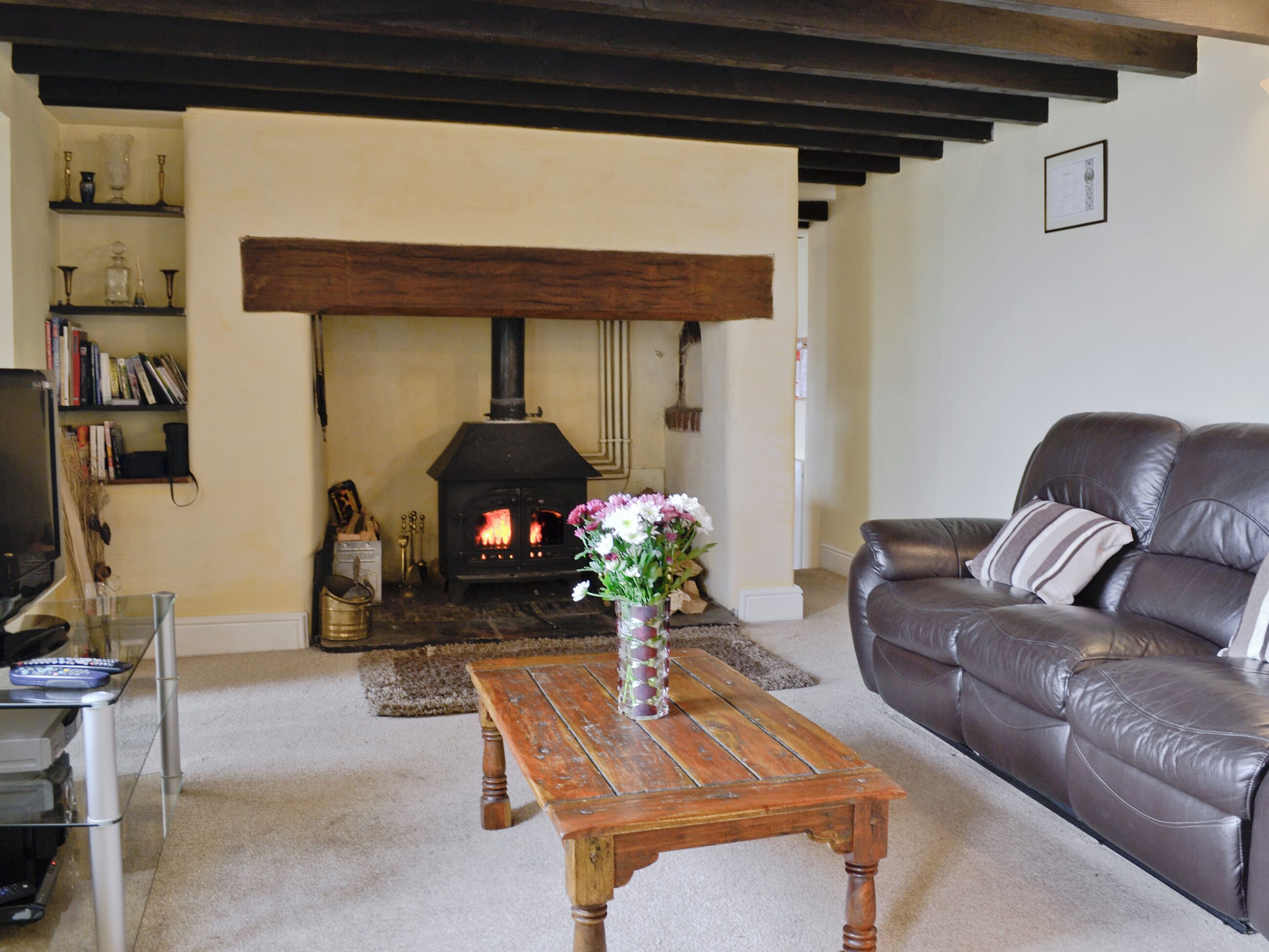 A living room with a fireplace, a leather sofa, a wooden coffee table, and a bookshelf.