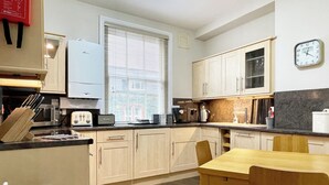 A compact kitchen with a dining area, featuring a microwave, toaster, sink, and cabinets. - High Style Apartment (Keswick)