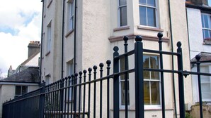 A building with a black metal fence, multiple windows, and a beige facade. - High Style Apartment (Keswick)