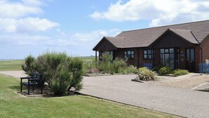 A brick building with a tiled roof, a gravel driveway, and a bench in the foreground. - 2 bedroom accommodation in Walcott (Walcott)