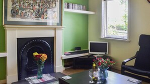Un salon avec une cheminée, une bibliothèque, un téléviseur et une fenêtre avec des stores.