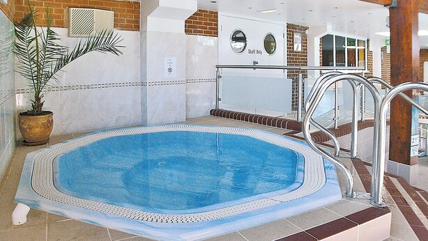 Una piscina interior con suelo de baldosas, una planta en maceta y un cartel que dice 'Staff Only'.