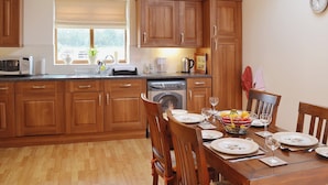 Cucina con mobili in legno, un tavolo da pranzo per quattro persone e una lavatrice.