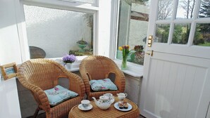 Una habitación con dos sillones de mimbre, una mesita con juego de té y una puerta blanca.