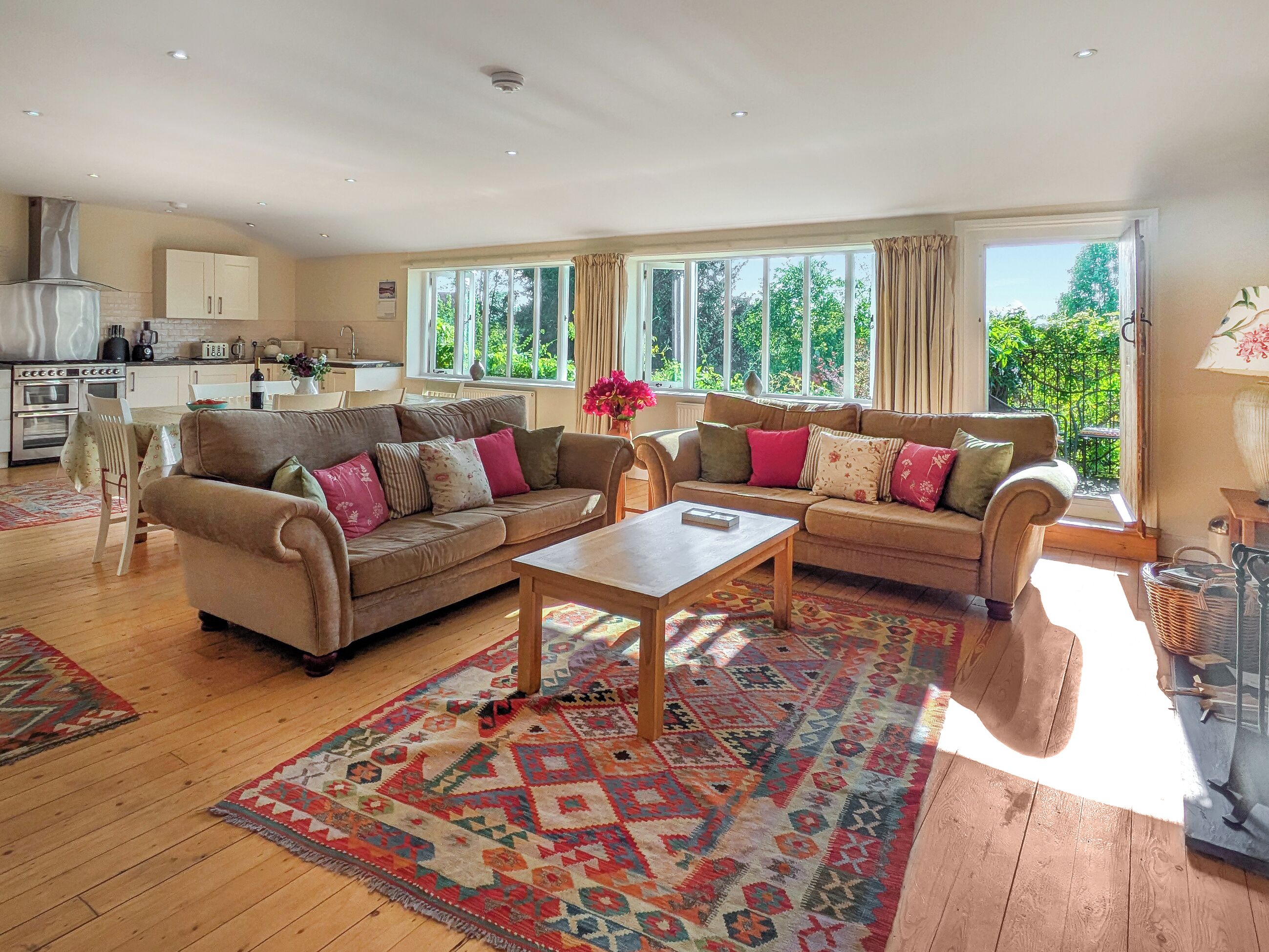 A spacious living room with two sofas, a coffee table, and a dining area with a kitchen in the background.
