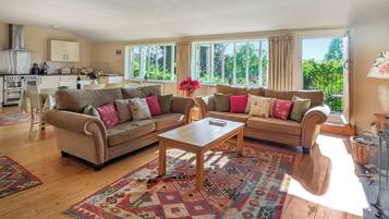 A spacious living room with two sofas, a coffee table, and a dining area with a kitchen in the background.