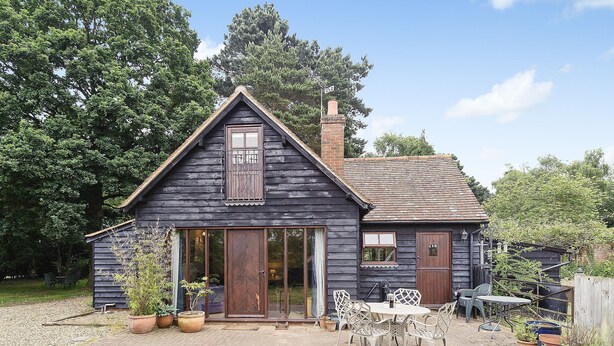 A wooden house with a large front door, a chimney, and a small porch with chairs. - 3 bedroom accommodation in Bromeswell, Woodbridge (Bromeswell, Woodbridge)