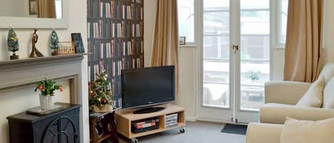 Una sala de estar con chimenea, televisor, estantería y sofá.