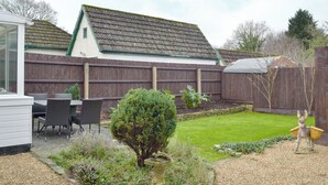 A backyard with a patio area, a wooden fence, and a small garden.