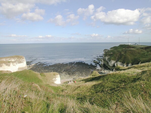 A coastal landscape with cliffs, a beach, and a clear sky.