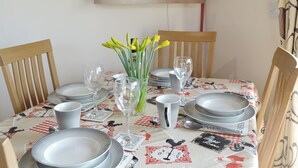 A dining table set with plates, glasses, and a vase of flowers. - Kingfisher Cottage - 25114 (Flamborough)