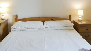 A neatly made bed with white linens and two bedside tables with lamps. - Kingfisher Cottage - 25114 (Flamborough)