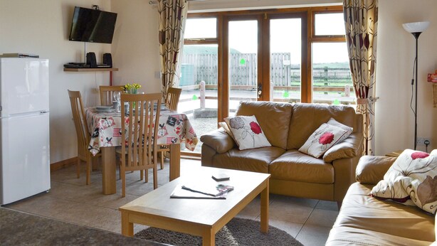 A cozy living room with a sofa, coffee table, and dining area. - Kingfisher Cottage - 25114 (Flamborough)