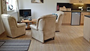 A living room with two leather chairs, a wooden coffee table, and a flat-screen TV.
