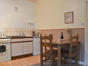 A compact kitchen with a washing machine, a sink, and a dining table with chairs.