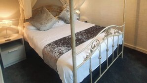 Un lit à baldaquin, une table de chevet et une petite table d’appoint.